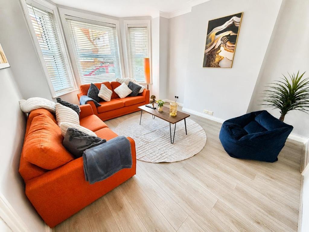 Modern living room with orange and navy upholstered seating, wooden floor, round area rug, and potted plant