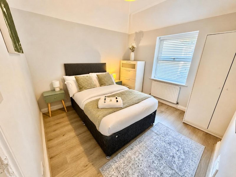 Bright bedroom with double bed, wooden floor, bedside table and wardrobe