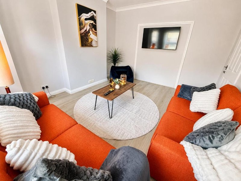 Modern living room with orange sofas, wooden coffee table, round rug and decorative cushions