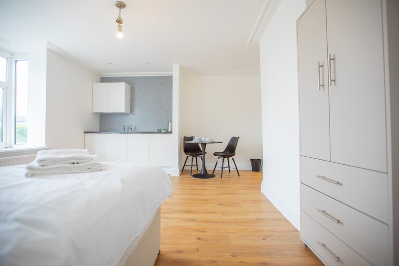 Studio apartment with bed, kitchenette, dining table, and wooden flooring throughout