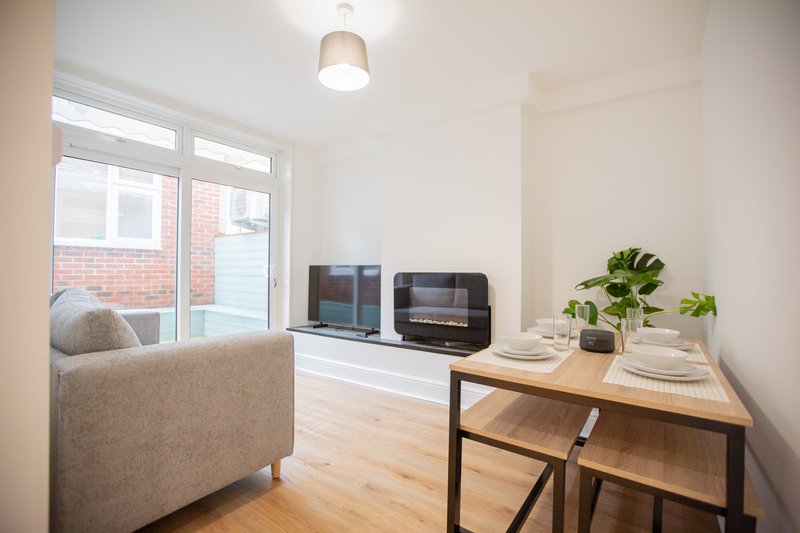 Open-plan living area with beige armchair, dining table, and television setup