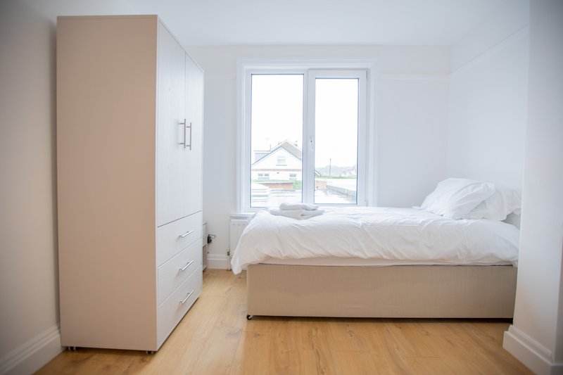 Bright modern bedroom with double bed, built-in wardrobe, wooden floor and patio doors