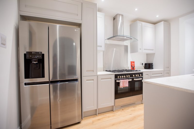 Modern kitchen with stainless steel appliances, white cabinetry, black range cooker and island