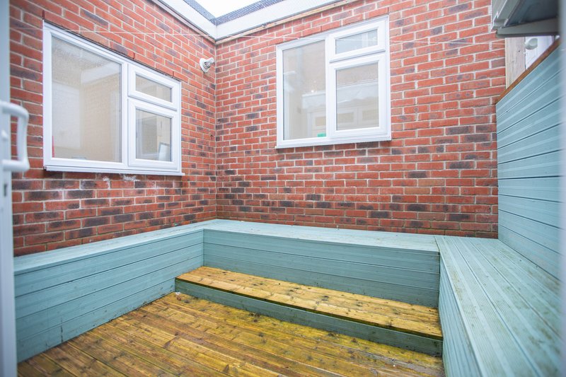 Empty brick and wood-panelled room with two windows and wooden flooring