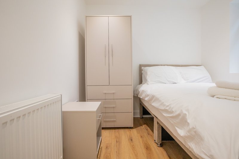 Bright bedroom with double bed, wooden floor, wardrobe and radiator