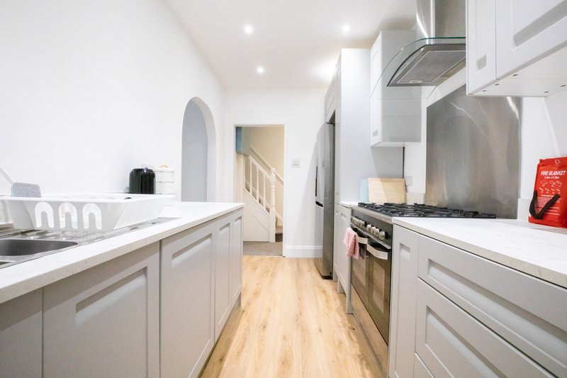 Modern galley kitchen with white cabinetry, stainless steel appliances and wooden flooring