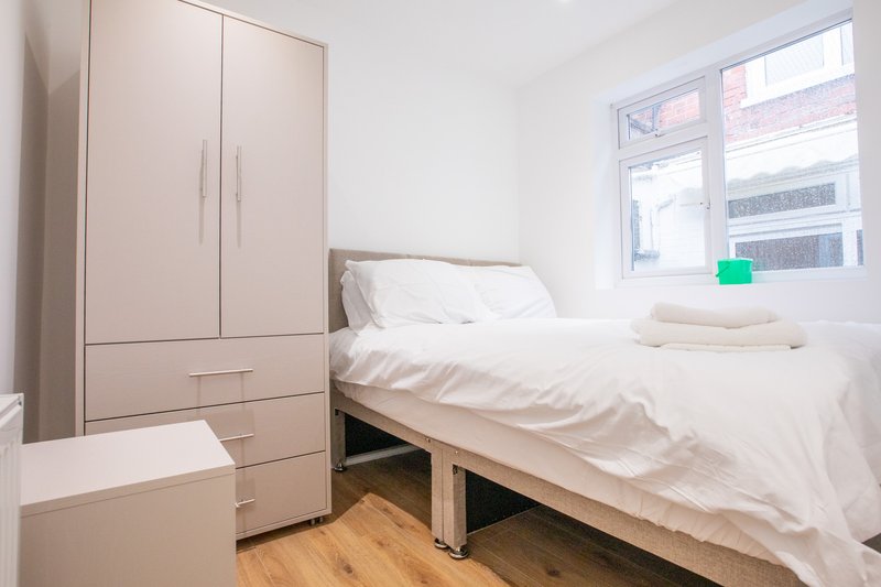 Bright bedroom with single bed, white bedding, wooden floor, and built-in wardrobe