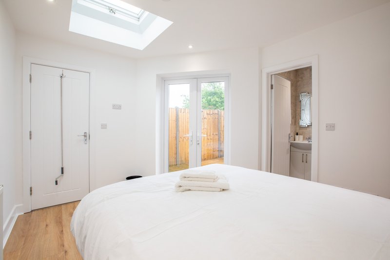 Bright modern bedroom with double bed, wooden floor, skylight and ensuite bathroom door