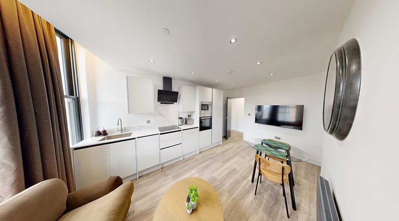 Open-plan kitchen and living area with white cabinetry, wooden flooring, and modern furnishings