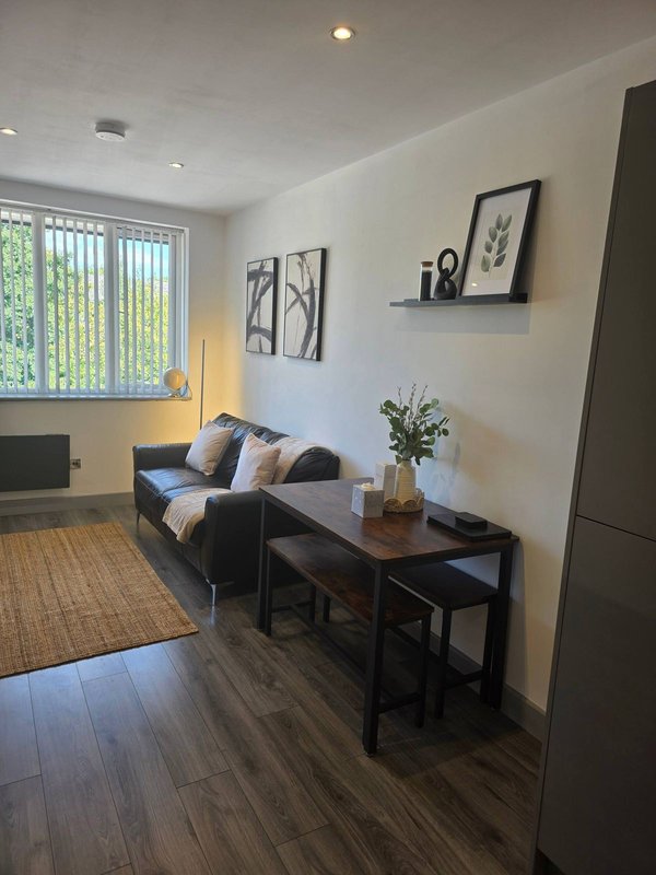 Modern living room with dark sofa, wooden coffee table, framed wall art, and vertical blinds at window