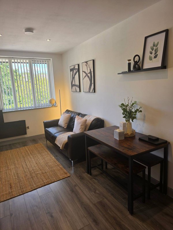 Modern living room with black sofa, dark wooden table, wall art and potted plant