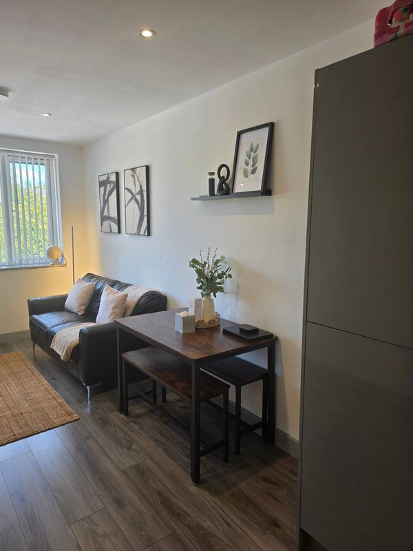 Living room with black sofa, wooden table, framed wall art and potted plant