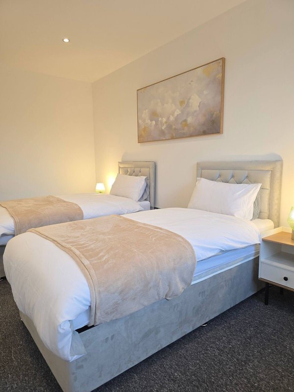 Twin bedroom with two beds, white bedding, neutral décor and wall art