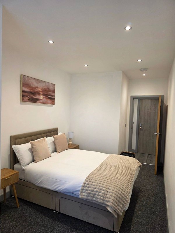 Modern bedroom with double bed, grey headboard, white bedding, and recessed ceiling lights