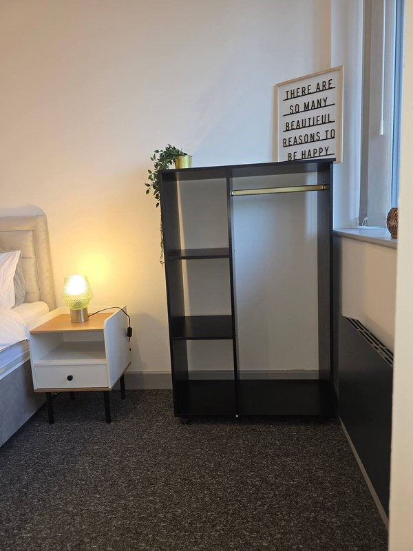 Bedroom with bed, nightstand, lamp, black wardrobe, and window