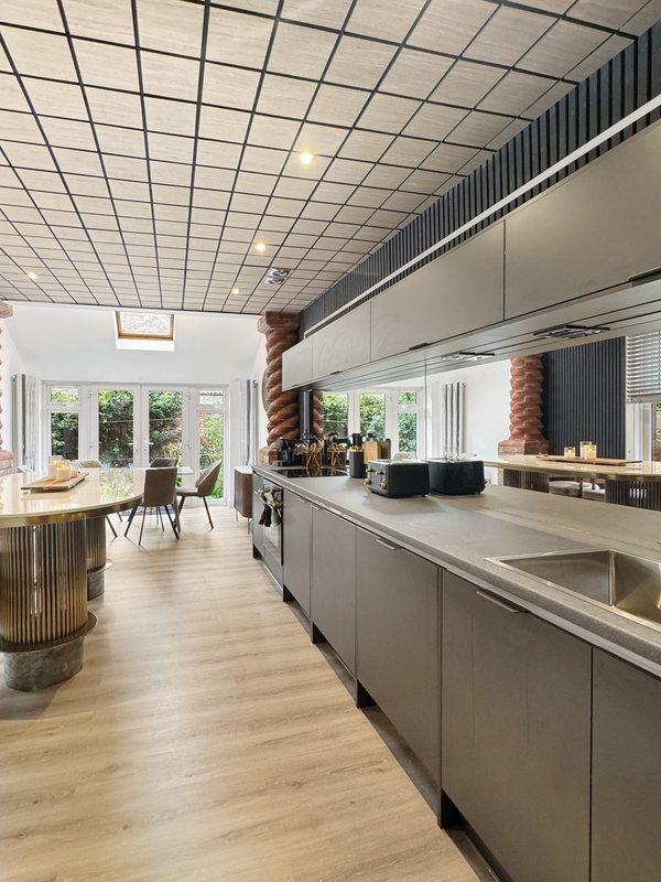 Modern open-plan kitchen and dining area with grey cabinetry, wooden flooring, and large windows