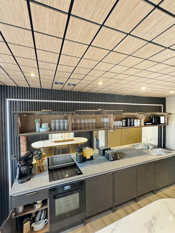 Modern kitchen with dark cabinetry, white countertop, wall shelving and integrated appliances