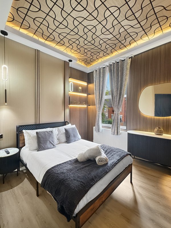 Modern bedroom with double bed, geometric ceiling design, and built-in wardrobe