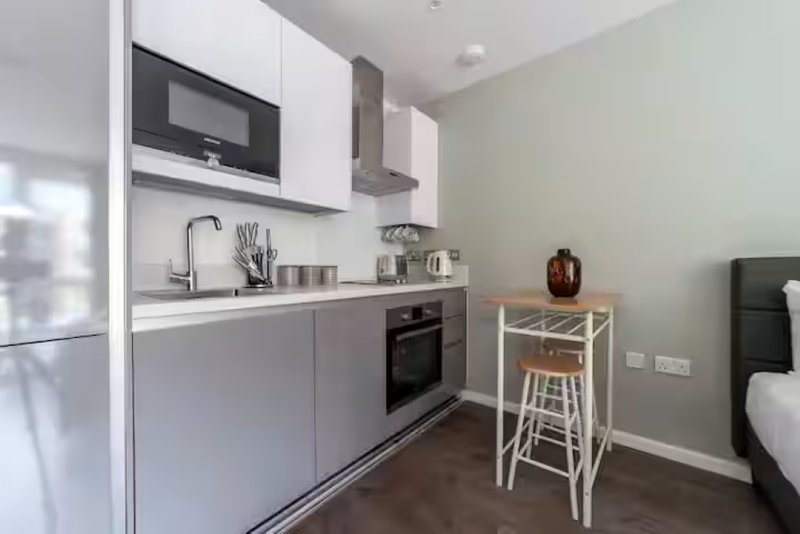 Modern kitchen with white cabinetry, black oven, breakfast bar with stools, and stainless steel appliances