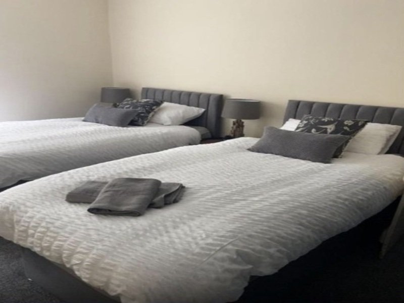 Twin beds with grey upholstered headboards, white bedding, and folded towels