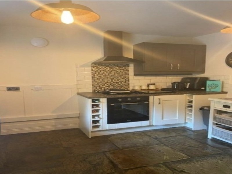 Modern kitchen with white and wood cabinetry, black oven, mosaic backsplash and pendant lighting
