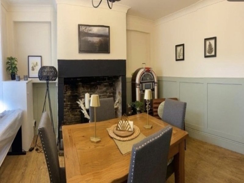 Dining room with wooden table, fireplace, framed wall art, and panelled walls