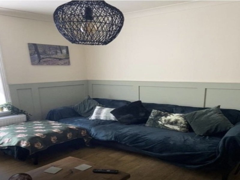 Living room with blue corner sofa, patterned cushions, woven ceiling pendant light and wall art