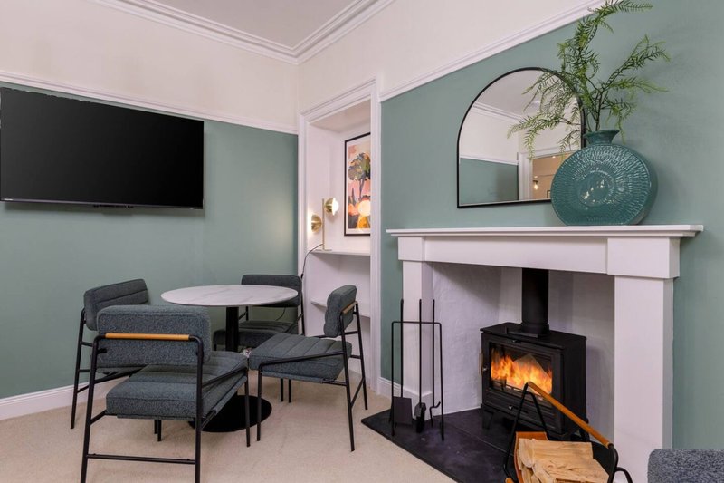 Modern living room with fireplace, dining table, chairs, wall-mounted TV and decorative mirror