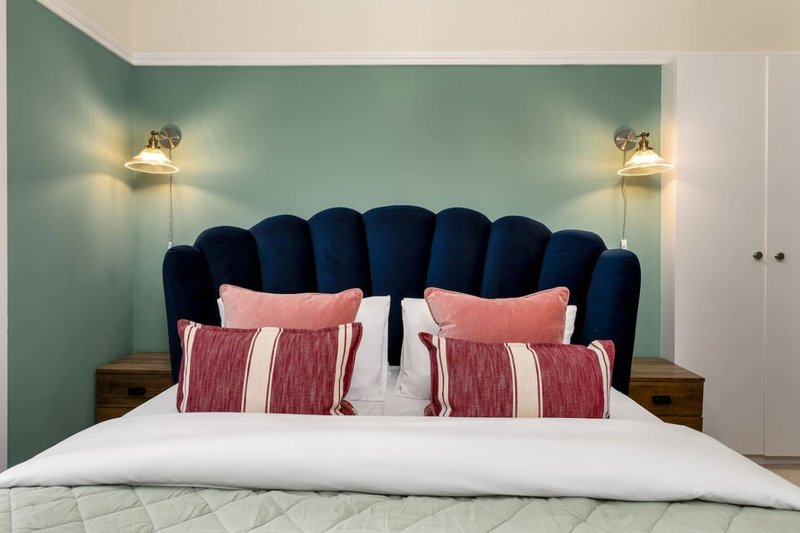 Bedroom with teal accent wall, navy upholstered headboard, white bedding, and decorative pillows