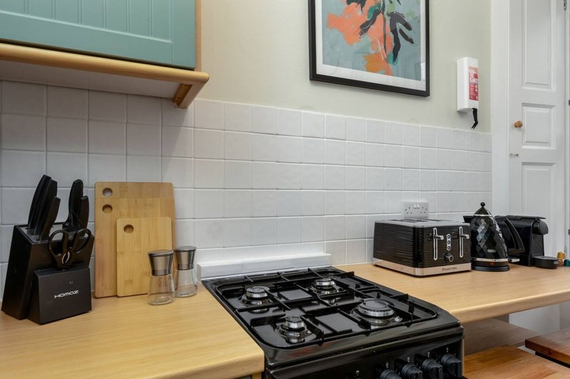Modern kitchen with gas hob, wooden countertop, knife block, and small appliances