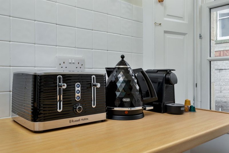 Kitchen countertop with black and wood kettle, toaster, and coffee maker appliances