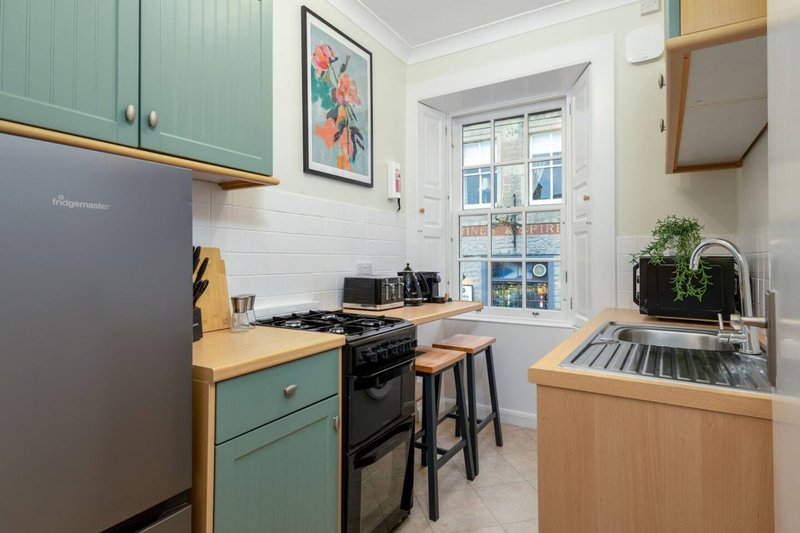 Modern kitchen with teal cabinetry, wooden countertops, black range cooker and white subway tile backsplash