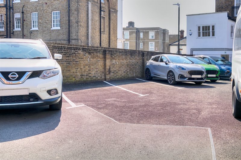 Shared driveway and parking area with multiple vehicles and brick buildings