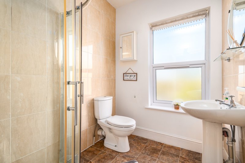 Modern bathroom with toilet, pedestal sink, shower enclosure and window