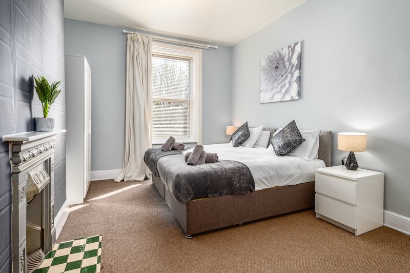 Bright bedroom with double bed, fireplace, window with curtains and bedside lamp
