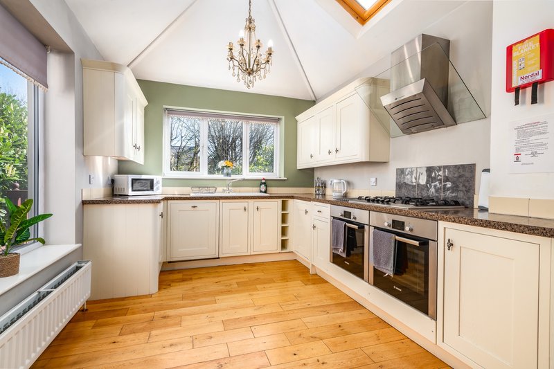 Modern kitchen with cream cabinets, wooden floor, green feature wall and double oven