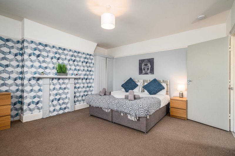 Spacious bedroom with double bed, blue patterned partition screen, wooden nightstands and carpet flooring
