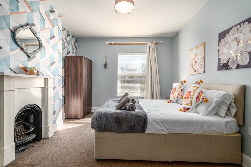 Bedroom with double bed, fireplace, window with curtains and decorative wall art