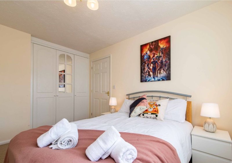 Bedroom with double bed, white wardrobe, bedside lamps, and wall art
