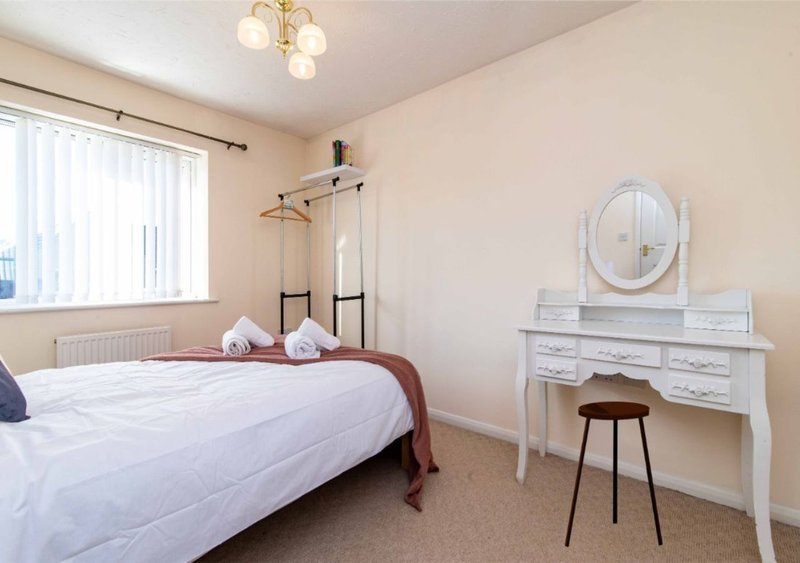 Bedroom with double bed, white dressing table, round mirror and pendant ceiling light