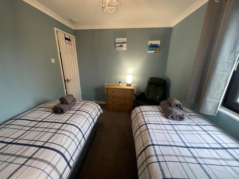 Twin bedroom with two single beds, wooden dresser, chair, and teal walls