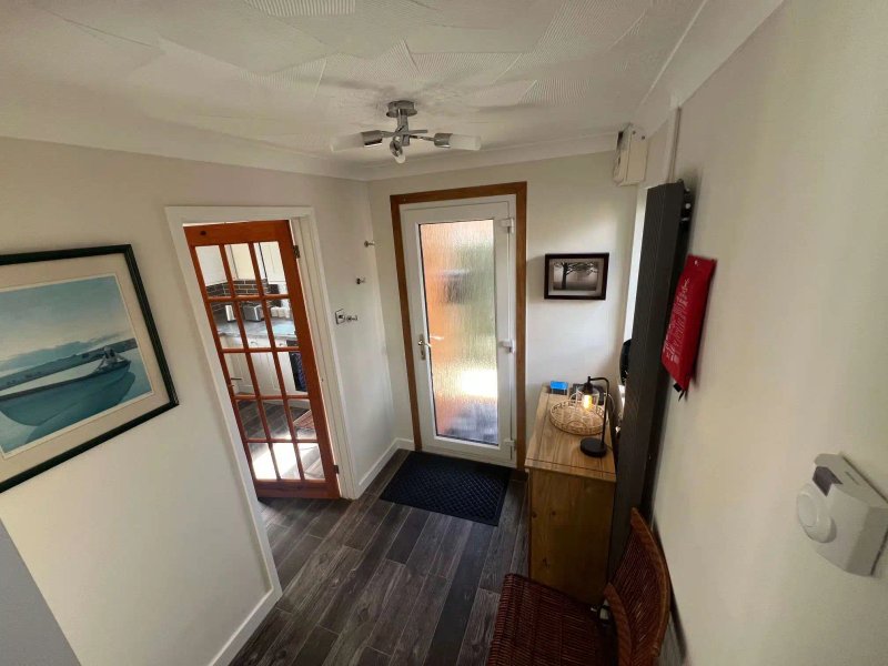 Hallway with wooden doors, dark flooring, framed artwork and ceiling fan