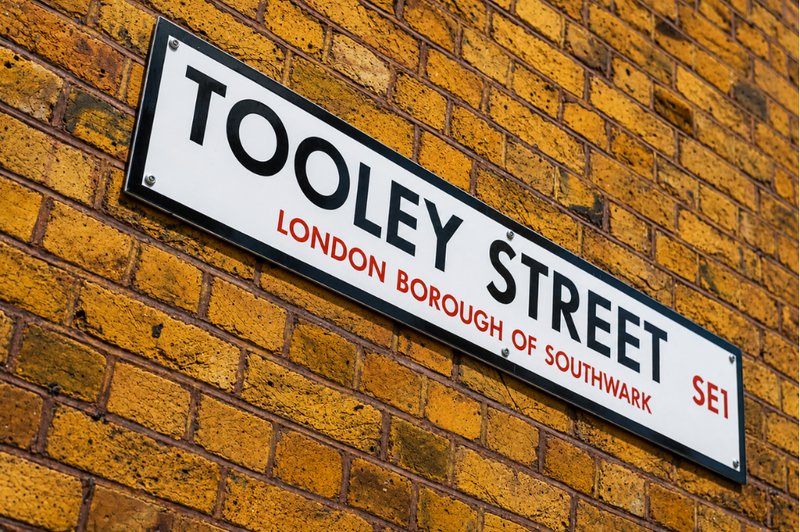 Tooley Street sign mounted on yellow brick wall, London location identifier