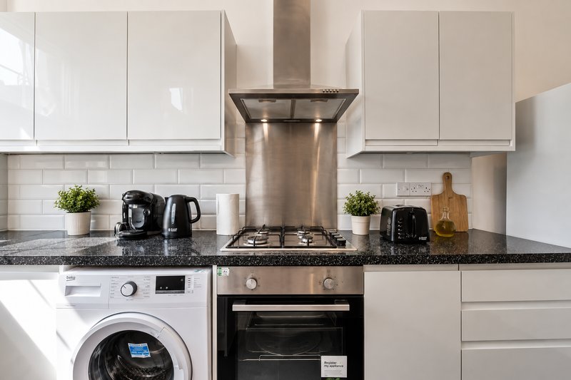 Modern kitchen with white cabinetry, stainless steel cooker hood, gas hob, and integrated appliances