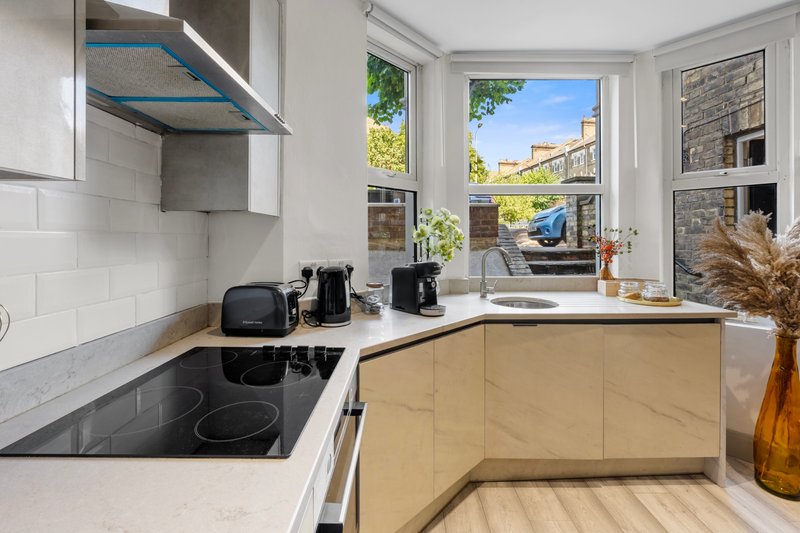 Modern kitchen with light wood cabinets, white countertops, induction hob and large windows with garden views