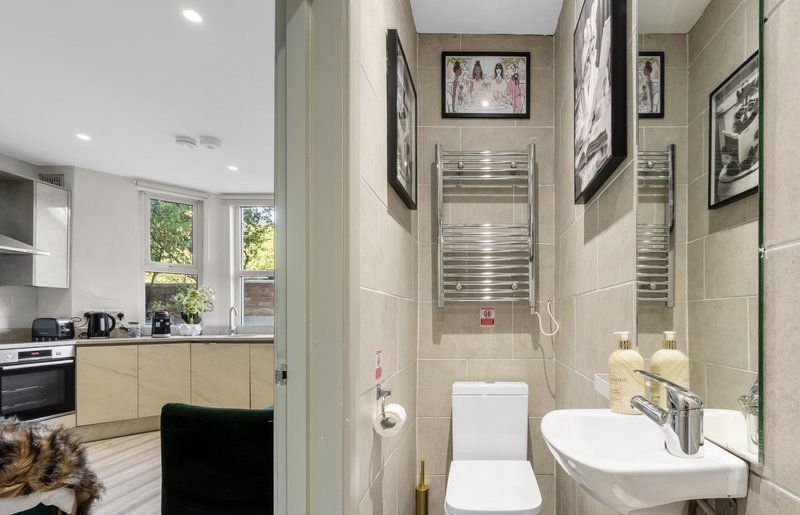 Modern bathroom with toilet, sink, heated towel rail and framed wall art