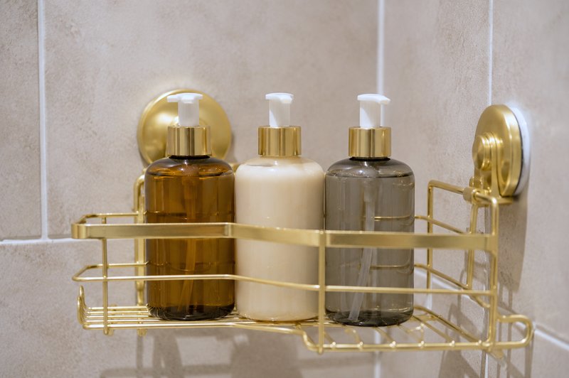 Bathroom shelf with four branded toiletry bottles in gold wire holder