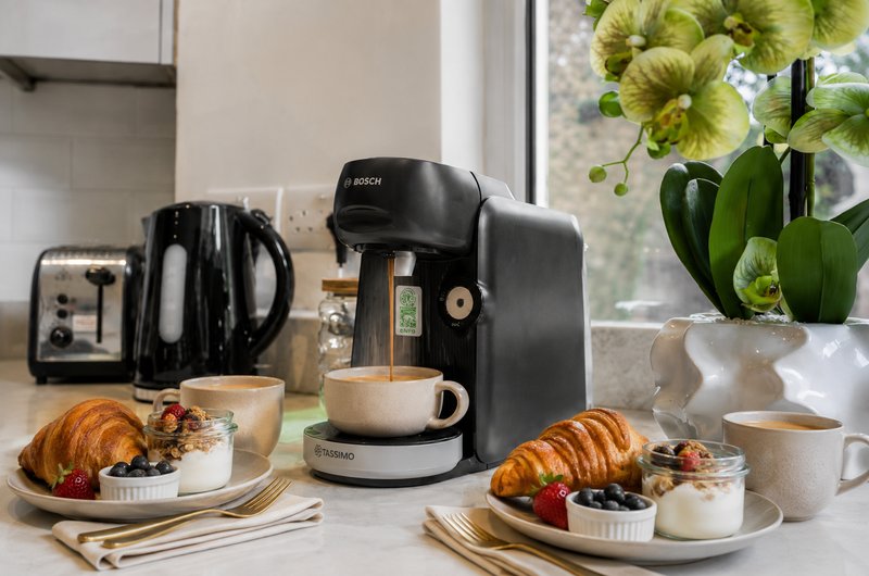 Kitchen counter with coffee maker, croissants, fresh flowers, and breakfast items by window