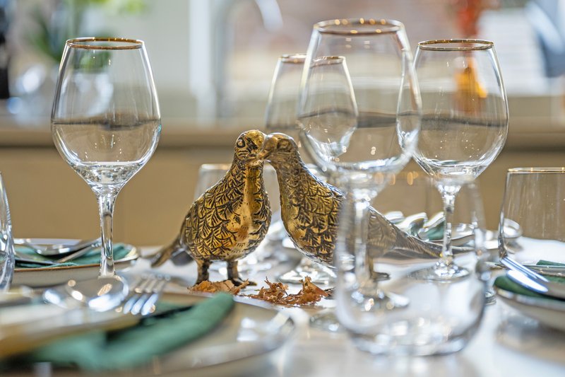 Formal dining table set with wine glasses, plates, cutlery and decorative gold bird figurine