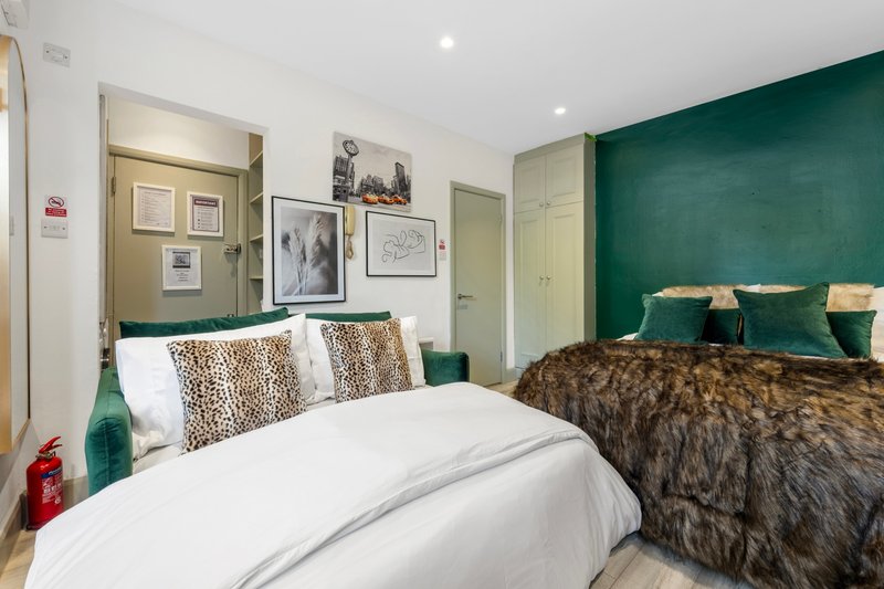 Modern bedroom with double bed, green accent wall, and decorative cushions and throws